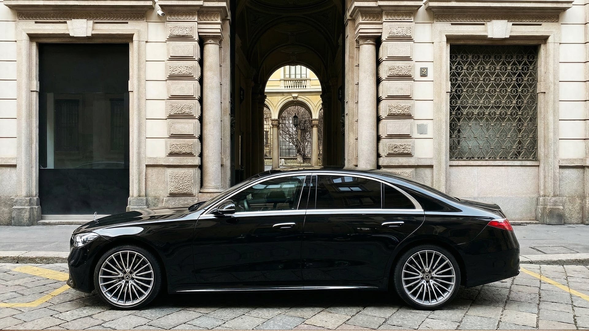 foto di macchina mercedes nera parcheggiata davanti a un edificio antico